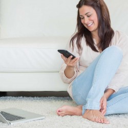 happy woman at home on floor using phone